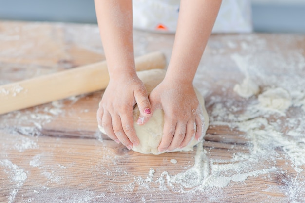 Las manos de los niños trabajan con masa y harina.