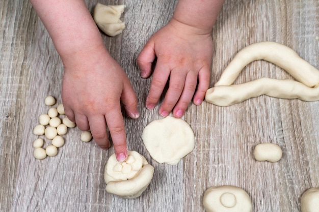 Las manos de los niños vuelan figuras de plastilina de arcilla de masa de sal sobre un fondo de madera Creatividad infantil Creatividad manual Esculpir en casa