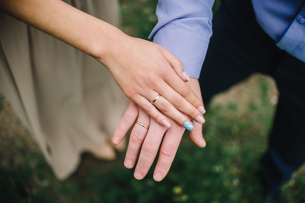 Manos de la novia y el novio con anillos de oro en la boda