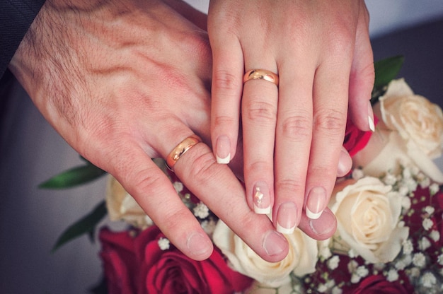 Manos de la novia y el novio con anillos de oro en los dedos