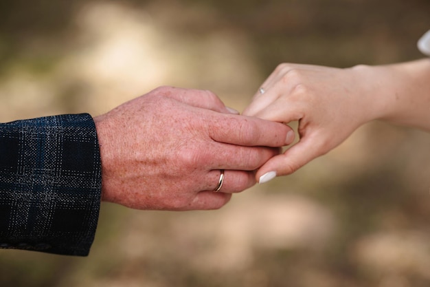 Las manos de la novia y el novio con anillos de oro se mantienen unidas el día de la boda