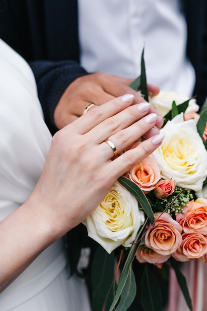 Manos de la novia y el novio con anillos en ramo de boda Concepto de matrimonio