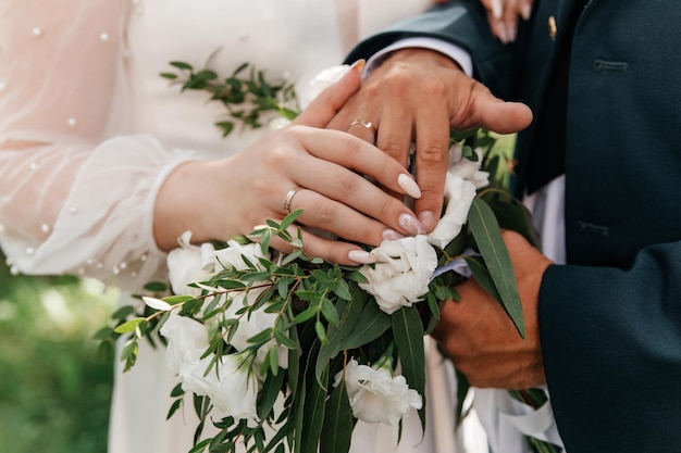 Manos de la novia y el novio con anillos en ramo de boda Concepto de matrimonio