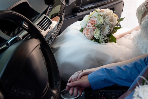 Manos de la novia y el novio en el auto en la boda