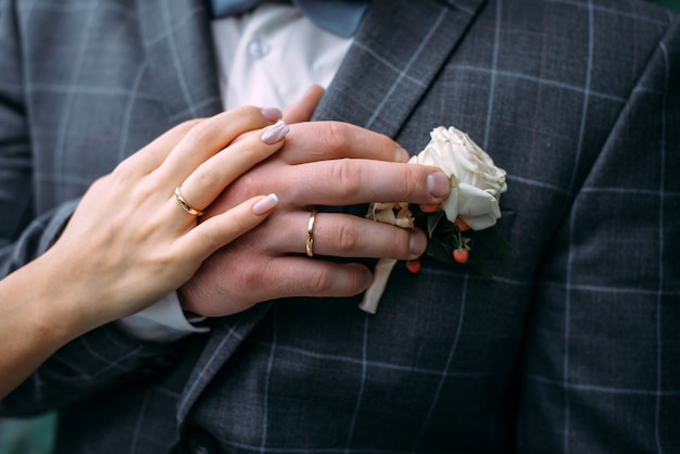 Manos de la novia y el novio con elegante manicura, primer plano. anillos de boda de los recién casados, pareja en el día de la boda, momento emotivo.