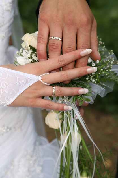 Manos de la novia y el novio junto al ramo de la boda