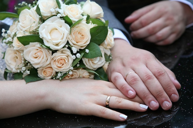 Manos de la novia y el novio junto al ramo de la boda