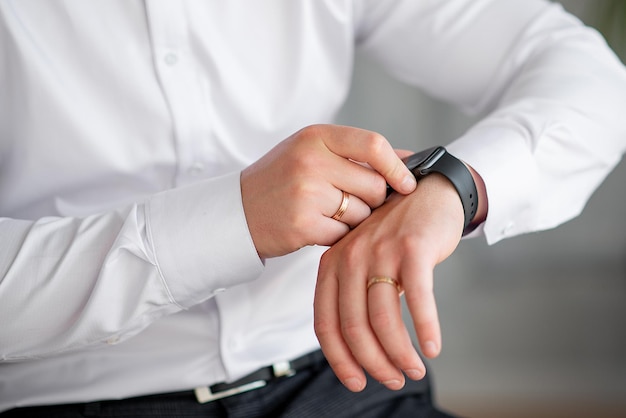 Manos del novio con una camisa blanca con un reloj y tarifas de anillo para el trabajo o el primer plano de la boda