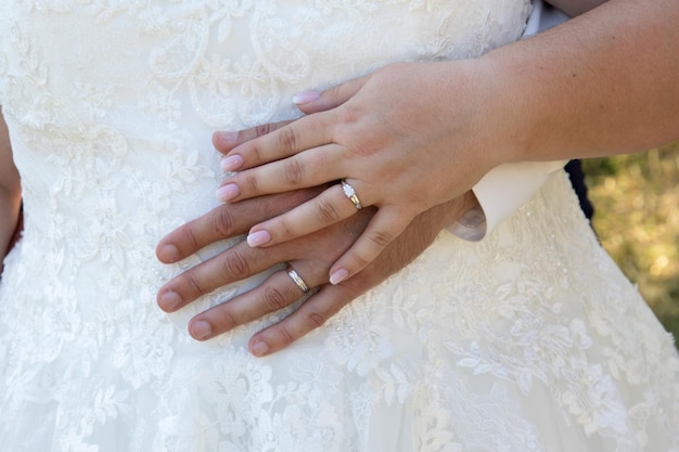 las manos del novio y la novia descansando en el vestido blanco con los anillos de boda matrimonio