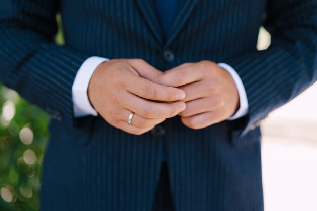 Manos del novio en un traje con un anillo en el dedo