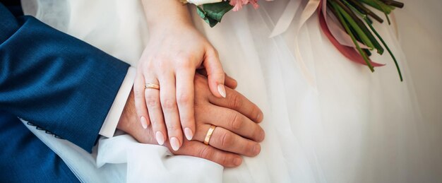 Manos de los novios con anillos de oro, primer plano. Abrazo de los recién casados. Creando una familia leal.