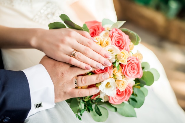 Manos de novios con anillos en el ramo de la boda. Concepto de matrimonio