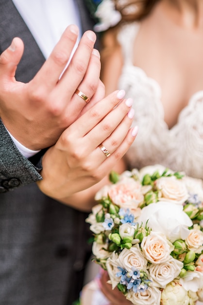 Foto manos de novios con anillos en el ramo de la boda. concepto de matrimonio.