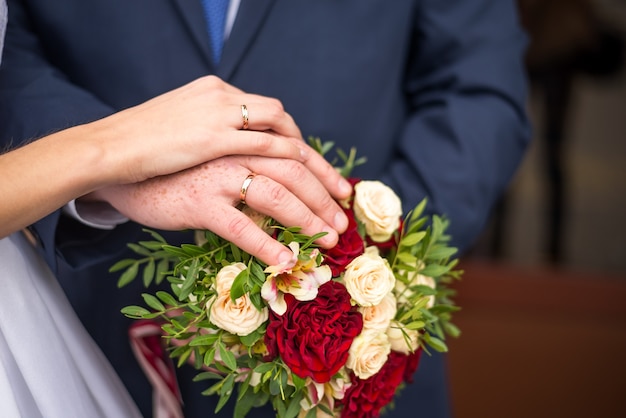 Manos de novios con anillos en ramo de novia. Concepto de matrimonio.