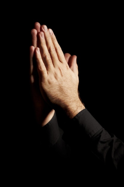 Las manos de oración y fondo negro para la esperanza religión y fe o pedir ayuda con el culto o apoyo espiritual en el estudio orando emoji persona cristiana y Dios perdone o la humanidad en la habitación oscura