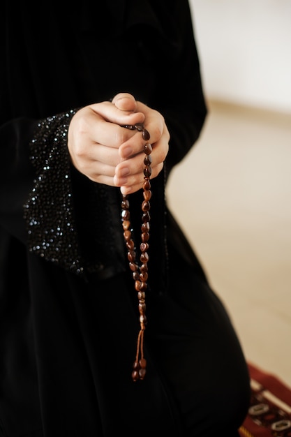 Manos de oración de una mujer sosteniendo un rosario.
