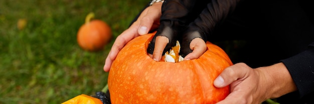 Manos de padre e hija tallando calabaza para Halloween Prepara Jack oLantern