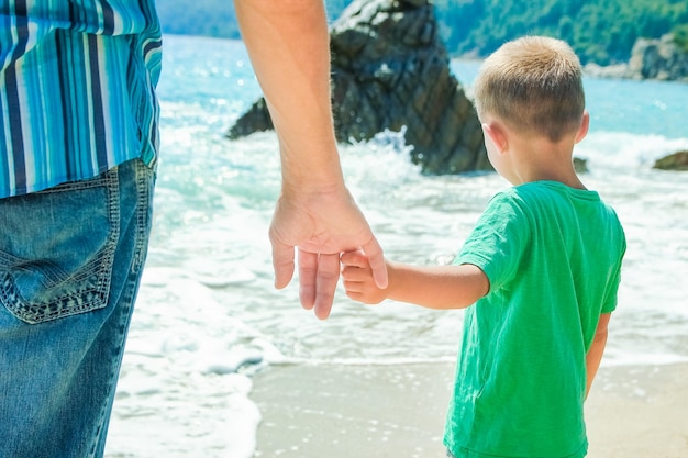 Manos de un padre feliz y un niño a la orilla del mar en un viaje de viaje en la naturaleza