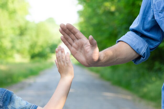 Las manos de un padre y un hijo felices en la naturaleza en el parque de viajes