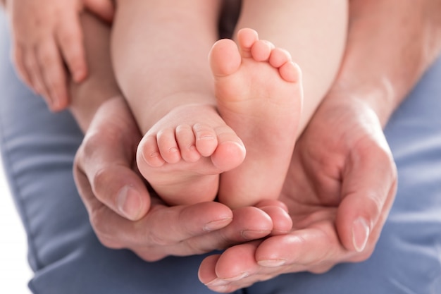 Las manos del padre sosteniendo los pies de su bebé