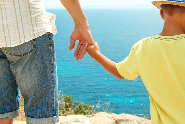 Manos de padres e hijos felices en el mar en antecedentes de viaje en grecia