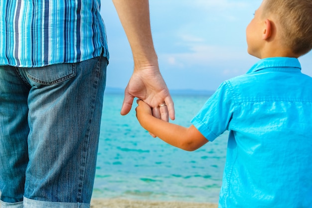 Manos de padres e hijos felices en el mar de fondo de Grecia