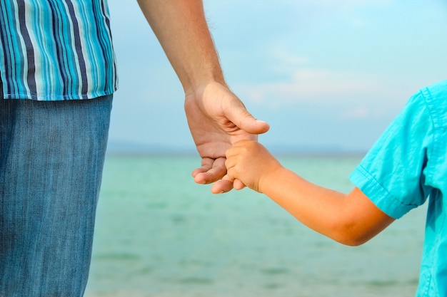 Manos de padres e hijos felices en el mar de fondo de Grecia