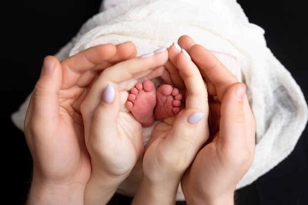 manos de padres e hijos. piernas de un recién nacido en manos de mamá y papá. las piernas del bebé en las manos.