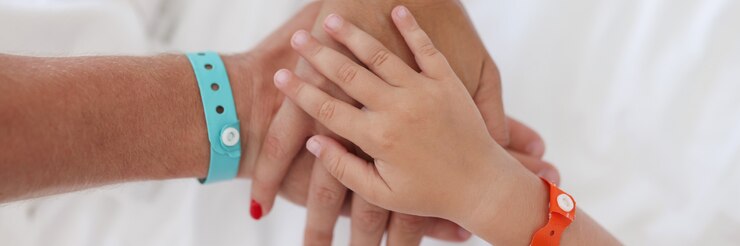 Foto las manos de los padres y el niño con pulsera están unidas.