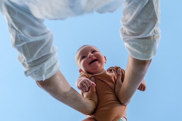 Manos de padres recogiendo a un bebé feliz