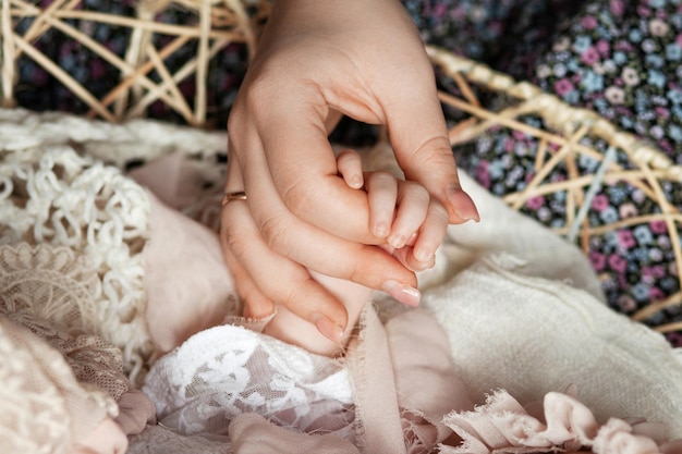 Manos de los padres sosteniendo los dedos del bebé recién nacido Cerrar la mano de la madre sosteniendo a su bebé recién nacido Amor a la atención médica familiar y parte del cuerpo médico