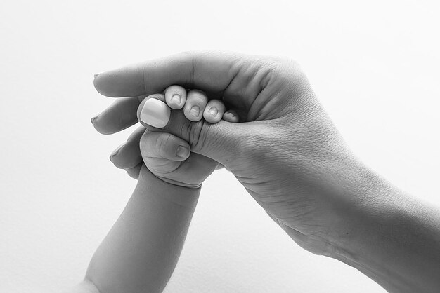 Foto las manos de los padres sostienen los dedos de un bebé recién nacido la mano de una madre y un padre en primer plano sostiene el puño de un bebé recién nacido salud familiar y atención médica dedos diminutos en una foto en blanco y negro