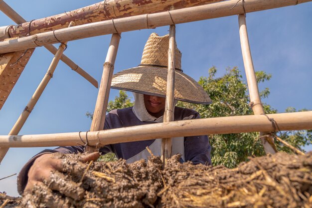 Manos en una pared de barro de una técnica de bioconstrucción de hombre latino