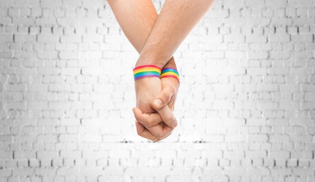 Foto manos de una pareja con pulseras de orgullo gay arco iris