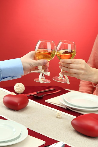 Manos de pareja romántica brindando con sus copas de vino sobre una mesa de restaurante