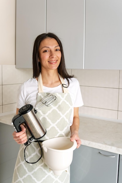 Manos de pastelero profesional femenino sosteniendo la batidora de mano