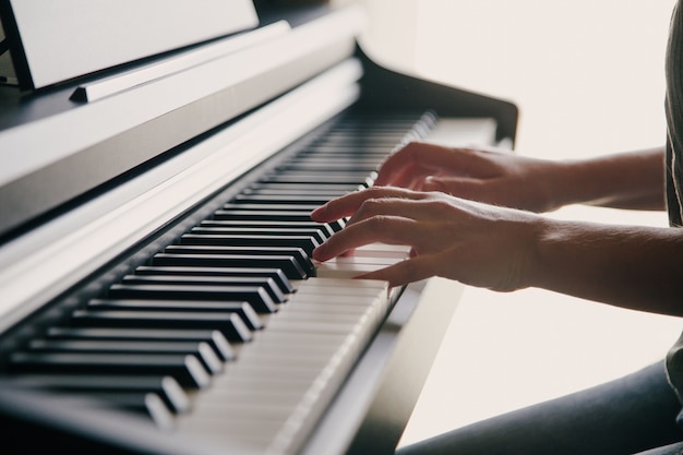 Manos de la persona caucásica tocando el piano. Concepto de aficiones