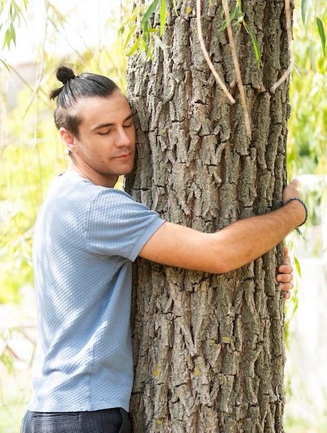 manos de personas abrazando el tronco de un árbol en un jardín