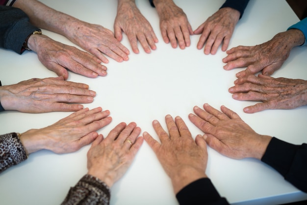 Manos de personas mayores en círculo juntos