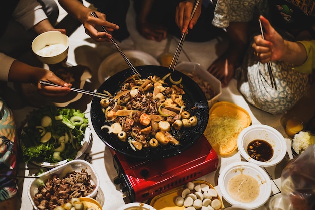 Manos de personas usando palillos con parrilla de barbacoa en una fiesta. Concepto de comida, gente y tiempo familiar.