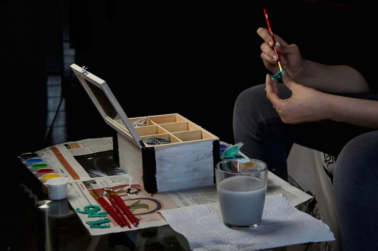 Foto manos pintando una caja y letras con acuarelas