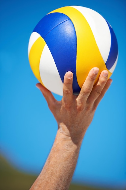 Manos de playa y persona deportiva con pelota de voleibol para competición de juego al aire libre o desafío de torneo Bienestar de verano cielo azul y jugador de voleobol de primer plano para ejercicio de fitness o entrenamiento activo