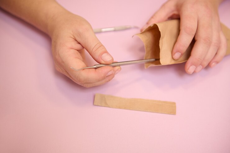 Foto manos del podólogo abriendo una bolsa con instrumentos de acero inoxidable estériles para una pedicura profesional. de cerca