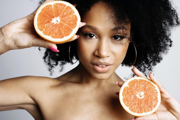 En manos de un pomelo naranja cítrico maduro Sesión de fotos en un estudio fotográfico sobre un fondo blanco