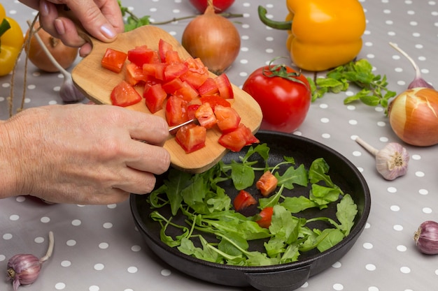 Foto las manos ponen tomates en la tabla de cortar.