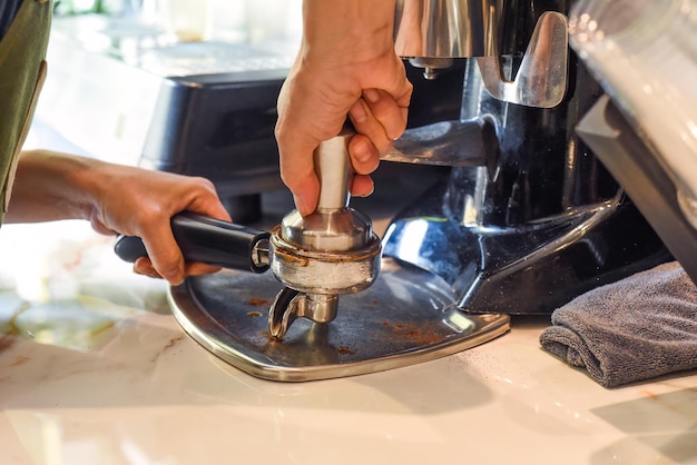 Manos presionando granos de café para cerrar una máquina de café