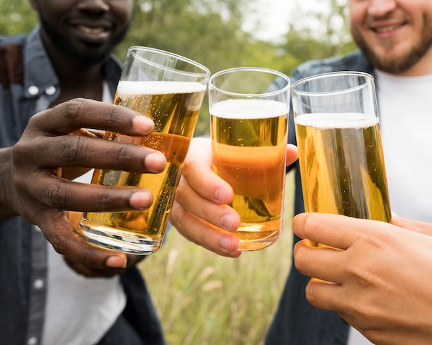 Manos de primer plano brindando con cerveza