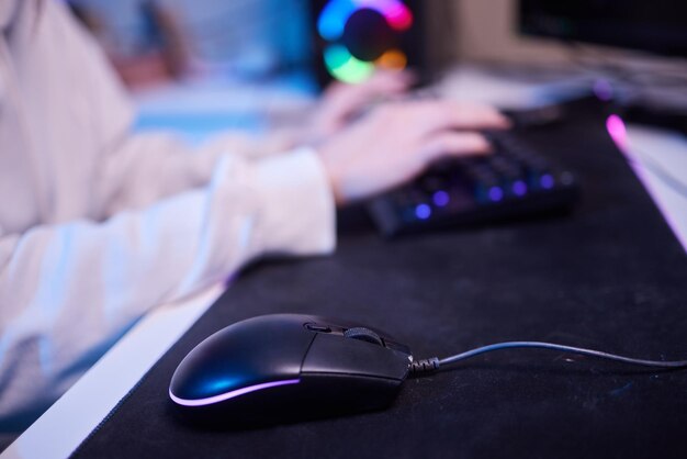 Las manos de primer plano dispararon a una chica de asia que usa el teclado y el controlador del mouse para jugar videojuegos con una computadora con luz de neón en el escritorio en casa Juego de transmisión de deportes en línea en línea Concepto de actividad de cuarentena en el hogar