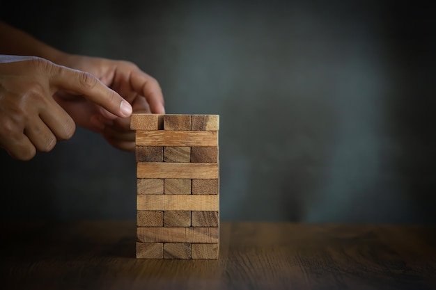 Las manos de primer plano evitan que el bloque de madera no se caiga