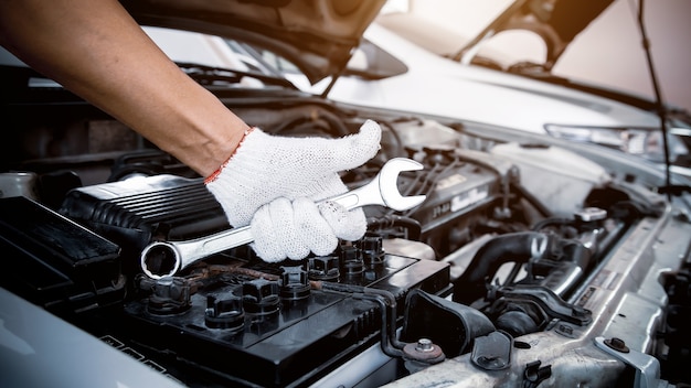 Manos de primer plano de mecánico de automóviles con la llave para el mantenimiento del motor del automóvil.